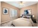 This staged bedroom features neutral walls, carpet, a ceiling fan, and artwork at 2784 Cherrydale Falls Dr, Henderson, NV 89052