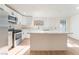 Spacious kitchen with white cabinets, stainless appliances, an island with quartz countertop and natural light from a window at 3320 Osage Ave, Las Vegas, NV 89101