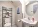 Cozy half bath featuring a pedestal sink, toilet with shelving, and neutral wall art at 4037 Asante Cove St, Las Vegas, NV 89115