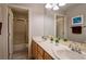 Well-lit bathroom featuring double sinks, wood cabinets, a large mirror, and a shower with glass doors at 464 Beardsley Cir, Henderson, NV 89052