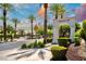View of the Carriage Lane community entrance featuring palm trees, lush landscaping, and a stone archway at 464 Beardsley Cir, Henderson, NV 89052