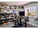 A bright home office is filled with natural light with shelving and a convertible standing desk and studio lighting at 464 Beardsley Cir, Henderson, NV 89052