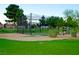 Practice facility with netted enclosure, manicured lawn, mature trees, and green shrubbery at 5028 Glenarden Dr, Las Vegas, NV 89130