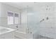 Luxurious bathroom featuring marble-look tiling, a soaking tub, and a glass-enclosed shower at 5116 Iron Crossing Ave, Las Vegas, NV 89131