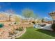 Landscaped backyard features artificial turf, desert plants, trees, slide, and outdoor dining area perfect for entertaining at 6688 Martinsville Pl, Las Vegas, NV 89110