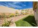 Manicured backyard with artificial turf, desert landscaping and retaining wall provides privacy and visual appeal at 6688 Martinsville Pl, Las Vegas, NV 89110