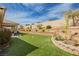 Expansive backyard features lush artificial turf and a charming terraced retaining wall with plants and desert landscaping at 6688 Martinsville Pl, Las Vegas, NV 89110