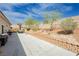 Large backyard with mature trees and desert landscaping along the retaining wall, and spacious patio with seating area at 6688 Martinsville Pl, Las Vegas, NV 89110