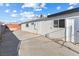 Long concrete driveway and backyard featuring white walls, a storage shed, and small windows at 704 Slayton Dr, Las Vegas, NV 89107