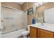 Compact bathroom featuring a shower-tub combination with sliding glass doors and neutral-toned decor at 7669 Fieldfare Dr, North Las Vegas, NV 89084