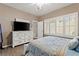 Comfortable bedroom with shutters, a large window, and a television on a white dresser at 7669 Fieldfare Dr, North Las Vegas, NV 89084