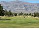 Picturesque golf course view with a distant mountain range, showcasing the green and mature trees at 7669 Fieldfare Dr, North Las Vegas, NV 89084
