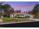 Charming single-story home featuring a lush green lawn, mature trees, and well-maintained landscaping at twilight at 9029 Rivers Edge Dr, Las Vegas, NV 89117
