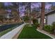 Charming home featuring landscaped front yard with green artificial turf and mature trees at 9029 Rivers Edge Dr, Las Vegas, NV 89117