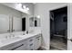Well-lit bathroom with double sinks, modern fixtures, and a view into an adjacent bedroom at 9349 Olympia Falls Ave, Las Vegas, NV 89149