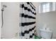 Clean bathroom with a shower featuring black and white striped curtains, and a toilet with extra toilet paper at 9349 Olympia Falls Ave, Las Vegas, NV 89149