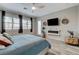Spacious main bedroom features a comfy bed, modern fireplace, and ample natural light at 9349 Olympia Falls Ave, Las Vegas, NV 89149