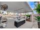 An inviting covered patio with comfortable seating, an outdoor kitchen, and a view of the sparkling pool and lush landscaping at 9349 Olympia Falls Ave, Las Vegas, NV 89149