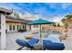 A resort-style backyard pool with a sun umbrella, lounge chairs, and rock features, perfect for outdoor relaxation and enjoyment at 9349 Olympia Falls Ave, Las Vegas, NV 89149