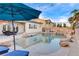 A private backyard pool with stone features, a sun umbrella, and an outdoor dining area, ideal for entertaining and relaxing at 9349 Olympia Falls Ave, Las Vegas, NV 89149