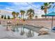 A luxurious backyard pool with rock waterfall features, a spa, lush landscaping, and ambient string lighting at 9349 Olympia Falls Ave, Las Vegas, NV 89149