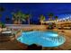 Inviting backyard pool and spa featuring lush landscaping and a cozy seating area illuminated by string lights at 9349 Olympia Falls Ave, Las Vegas, NV 89149
