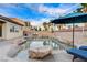 A relaxing backyard pool with stone accents, lounge chairs, lush landscaping, and ambient string lighting for a serene oasis at 9349 Olympia Falls Ave, Las Vegas, NV 89149