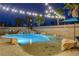 Backyard pool has rock features, lush landscaping, and string lights for evening ambiance at 9349 Olympia Falls Ave, Las Vegas, NV 89149