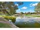 Picturesque pond view with mature trees, rock features and lush landscaping creating a serene atmosphere at 9937 Whalers Landing Ct, Las Vegas, NV 89117