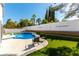 Backyard pool area with lush lawn, a white perimeter wall, and mature trees creating a private oasis at 9937 Whalers Landing Ct, Las Vegas, NV 89117