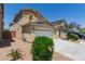 Two-story tan home with a two car garage, landscaping and a paved driveway at 104 Big Cliff Ave, North Las Vegas, NV 89031