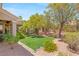 A peaceful backyard with a well-kept artificial lawn, natural desert landscaping, and mature trees at 10404 Long Leaf Pl, Las Vegas, NV 89134