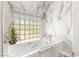 Bright bathroom featuring a walk-in tub, marble walls, and modern fixtures at 10404 Long Leaf Pl, Las Vegas, NV 89134