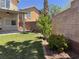 The backyard features a lawn, mature landscaping, a block wall, and covered patio at 11029 Meadow Leaf Ave, Las Vegas, NV 89144
