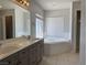 Bathroom featuring a double vanity, tiled floors, and large garden tub at 11029 Meadow Leaf Ave, Las Vegas, NV 89144