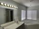 Bathroom featuring a dual sink vanity, large mirror and a soaking tub with natural light at 11029 Meadow Leaf Ave, Las Vegas, NV 89144