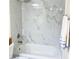 Updated bathroom featuring a soaking tub with elegant white marble-look tiling, modern fixtures and neutral colors at 11074 Caramel Crest Ct, Las Vegas, NV 89135