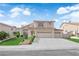 Beige two-story home with a three car garage and landscaping at 1611 Buffalo Trail Dr, Henderson, NV 89014