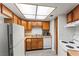 This is a well-lit kitchen, equipped with wood cabinetry, white appliances, and vinyl floors at 1628 Justin Ct # 18, Henderson, NV 89011