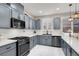 This kitchen has gray cabinets with stainless steel appliances and quartz countertops with a dark sink at 1763 Crystal Stream Ave, Henderson, NV 89012