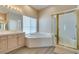 Bright bathroom featuring double sinks, soaking tub, and separate glass-enclosed shower for a spa-like experience at 2090 Eaglepath Cir, Henderson, NV 89074