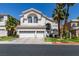 Beautiful two-story home featuring a three-car garage, manicured lawn and mature palm trees against a brilliant blue sky at 2090 Eaglepath Cir, Henderson, NV 89074
