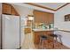 Kitchen with wooden cabinetry, breakfast bar, white appliances, and tile flooring at 22 Jade Cir, Las Vegas, NV 89106
