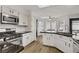 Bright kitchen featuring white cabinetry, black countertops, stainless steel appliances, and a breakfast bar at 270 Snowy River Cir, Henderson, NV 89074