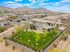 This aerial shows the back of the home with an artificial turf yard, trees, and mountain views in a neighborhood at 438 Wind Poppy St, Las Vegas, NV 89138