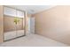 Tan bedroom with neutral carpet, mirrored closet, and a bright window view of a palm tree at 5615 Calais Ct, Las Vegas, NV 89118
