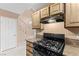 Kitchen featuring wooden cabinets, gas stove, granite countertops and staircase access at 5615 Calais Ct, Las Vegas, NV 89118