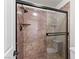 Modern bathroom shower features brown wall tiles, a glass sliding door, and updated fixtures at 5615 Calais Ct, Las Vegas, NV 89118