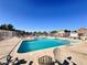 A community swimming pool surrounded by lounge chairs and a gated fence at 5653 Mount Athos St, North Las Vegas, NV 89031