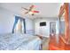 Bright main bedroom featuring a ceiling fan, television and ensuite door, with blue and gray color palette at 6233 Overhang Ave, Henderson, NV 89011